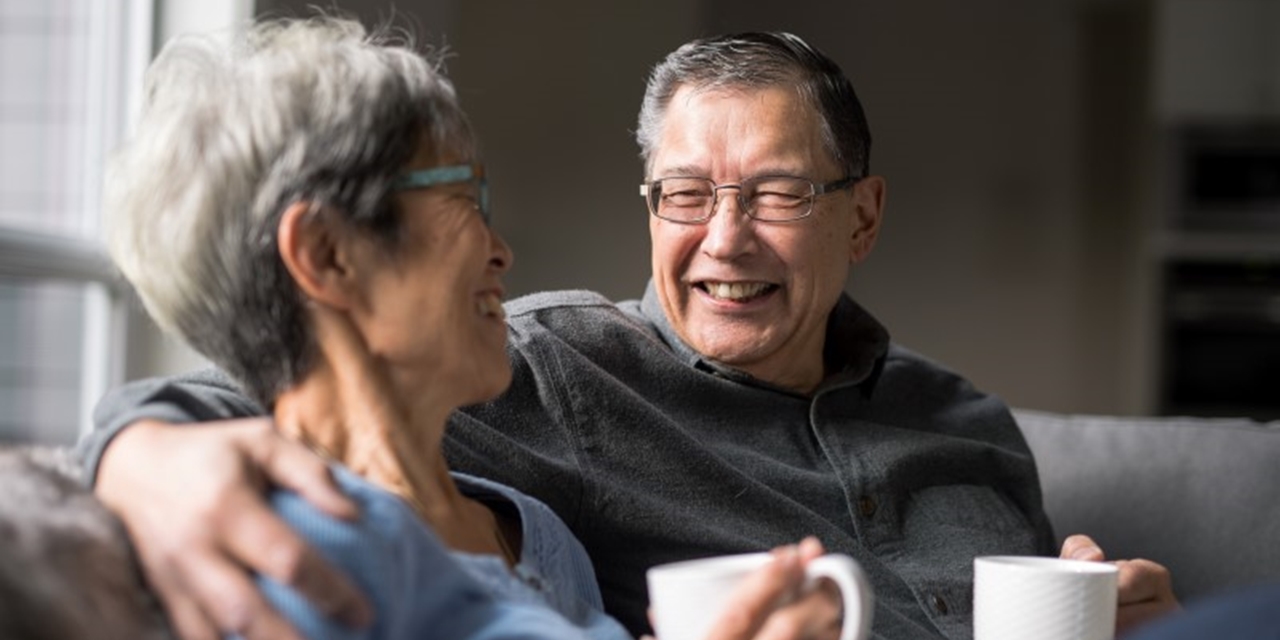 Older couple relaxing together on the sofa with a cup of tea