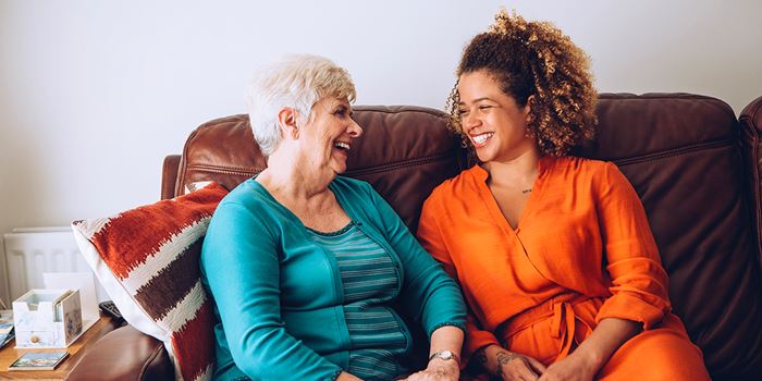 Resident and support officer smiling together on couch