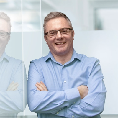 Photo of Neil Morland smiling in a blue shirt.