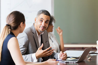 A man and woman talking at a board meeting