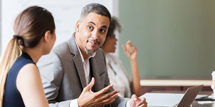 A man and woman talking at a board meeting