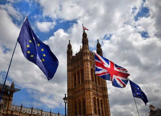 European Union and Union Jack flags flying in front of the Houses of Parliament in London