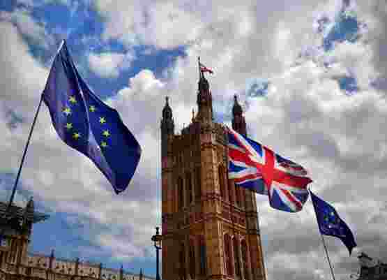 European Union and Union Jack flags flying in front of the Houses of Parliament in London