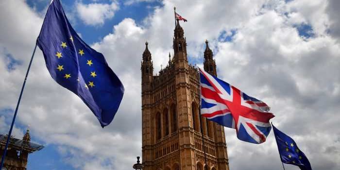 European Union and Union Jack flags flying in front of the Houses of Parliament in London