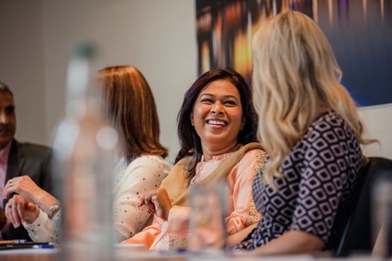 Smiling people in a meeting room with bottles of water on the table