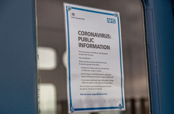 An A4 print out displayed in a door window with NHS information about coronavirus