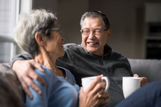 Older couple relaxing together on the sofa with a cup of tea