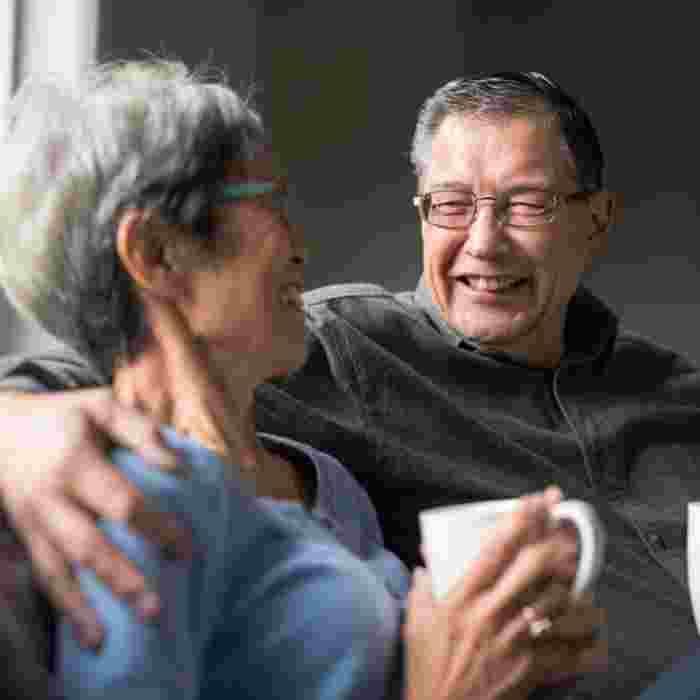 Older couple relaxing together on the sofa with a cup of tea