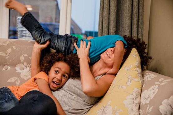 Children play with an adult on a sofa