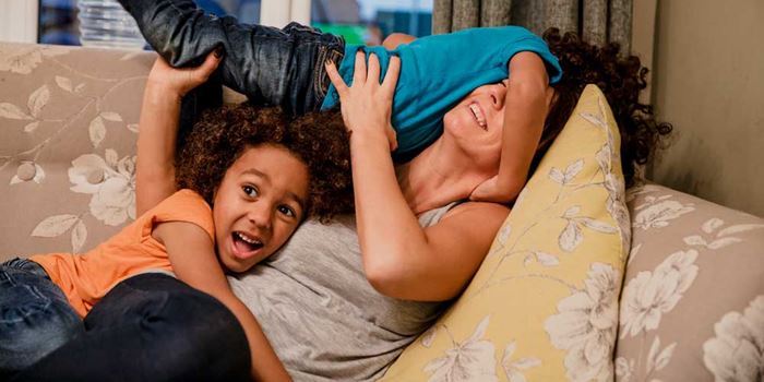 Children play with an adult on a sofa