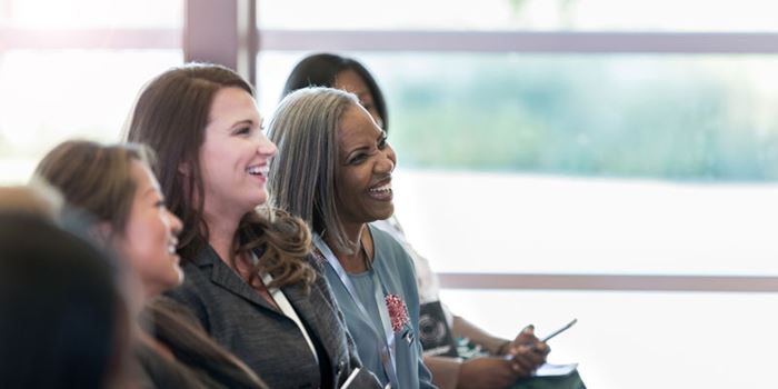 People sat in a row in front of a window enjoying an event