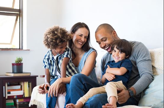 A young couple with young children on the sofa