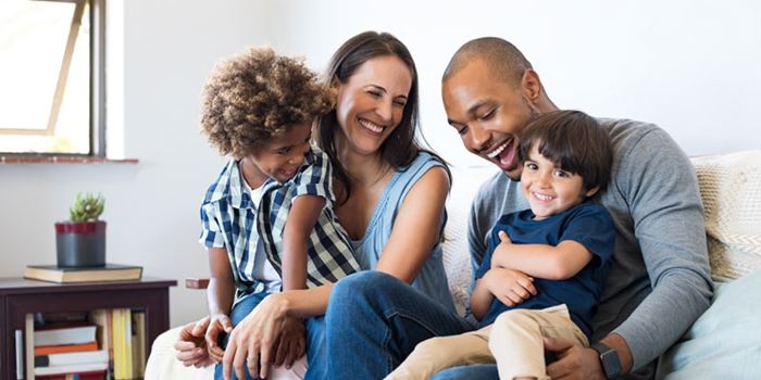 A young couple with young children on the sofa