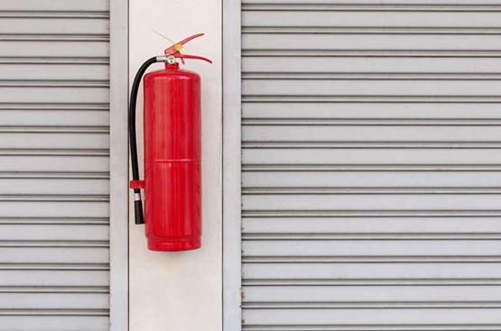 A red fire extinguisher fixed to a white wall