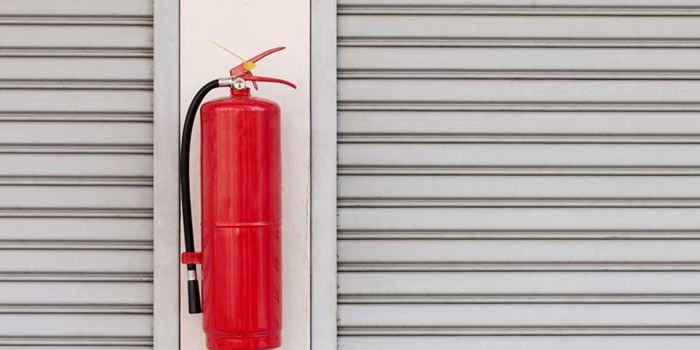 A red fire extinguisher fixed to a white wall