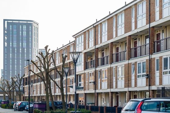 View down the road of a block of flats on the right and a tower block in the distance.