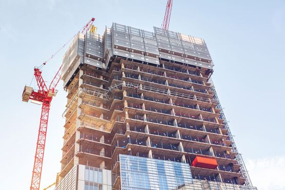 A block of flats under construction with a crane next to it