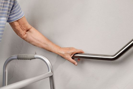 The hand of an older person on a hand rail