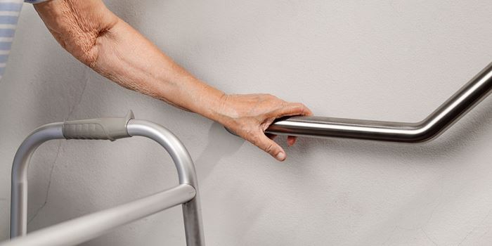 The hand of an older person on a hand rail