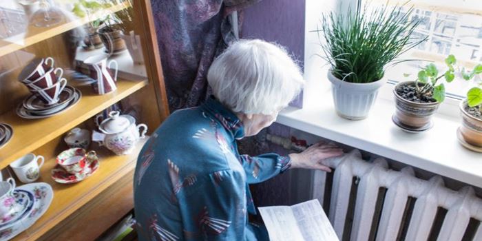Older person close to a radiator looking at an energy bill