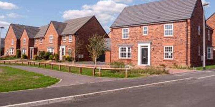 View of new build homes with a pathway in front of them and a blue sky behind