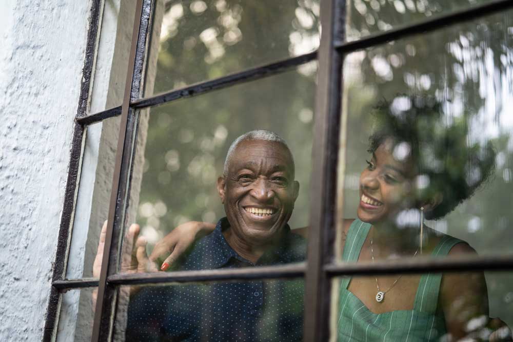 A man and a woman looking out of a window and smiling