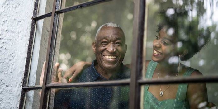 A man and a woman looking out of a window and smiling