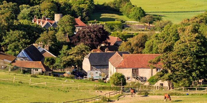 Rural scene featuring homes, hills, fields, trees and horses.