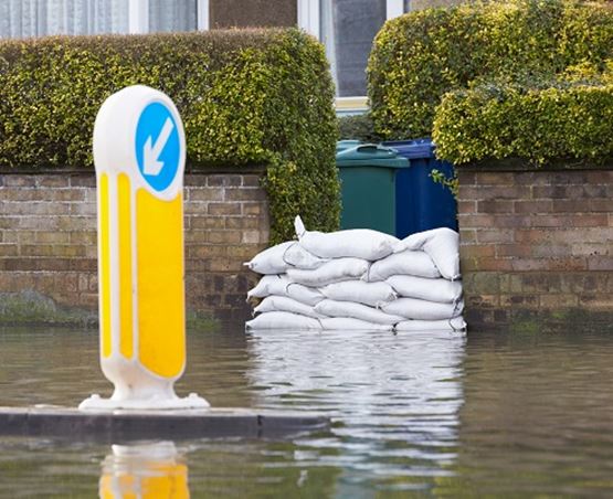 Sandbags piled up against the front door to a residental property, protecting the home from the surrounding flood water.