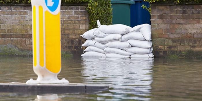 Sandbags piled up against the front door to a residental property, protecting the home from the surrounding flood water.