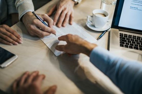 Hands signing paperwork