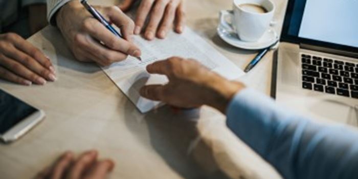 Hands signing paperwork