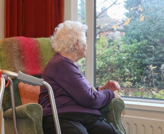 Lady looking out of a window from her home