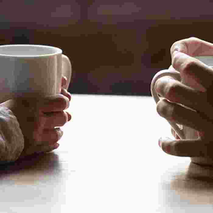 Two people holding cups with hot drinks